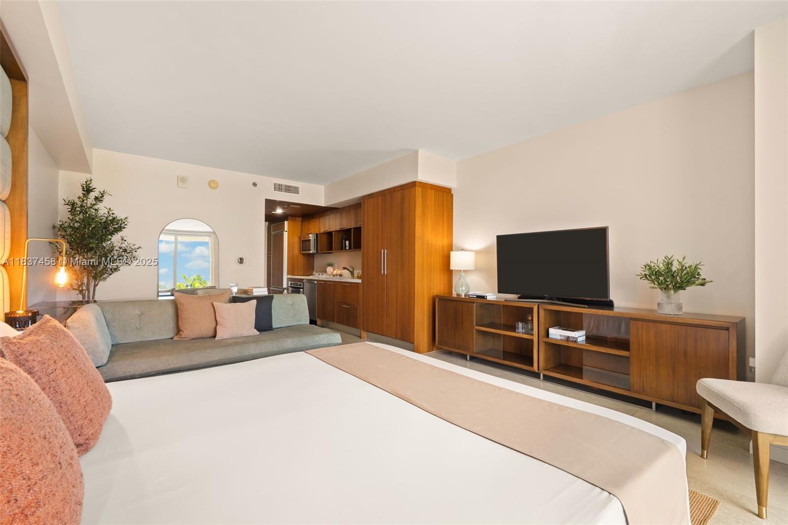 A hotel-style room features a bed, a sofa, a kitchenette, and a television console — 50 Biscayne Blvd # 411, Miami FL 33132, MIAMI, FL