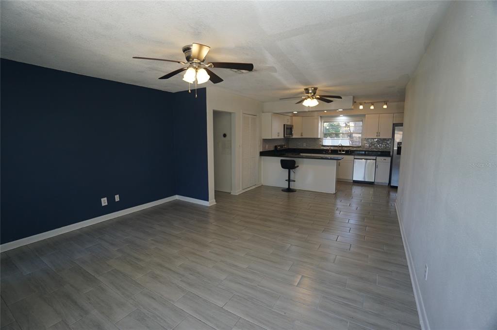 An open-concept living area features gray wood-look tile flooring, a navy accent wall, and kitchen — 3916 W NORTH A STREET, TAMPA, FL