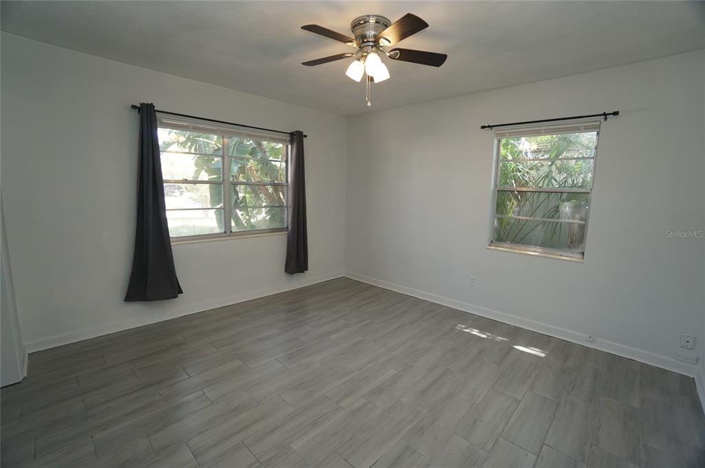 An empty bedroom features light gray wood-look tile flooring, white walls, and a ceiling fan — 3916 W NORTH A STREET, TAMPA, FL