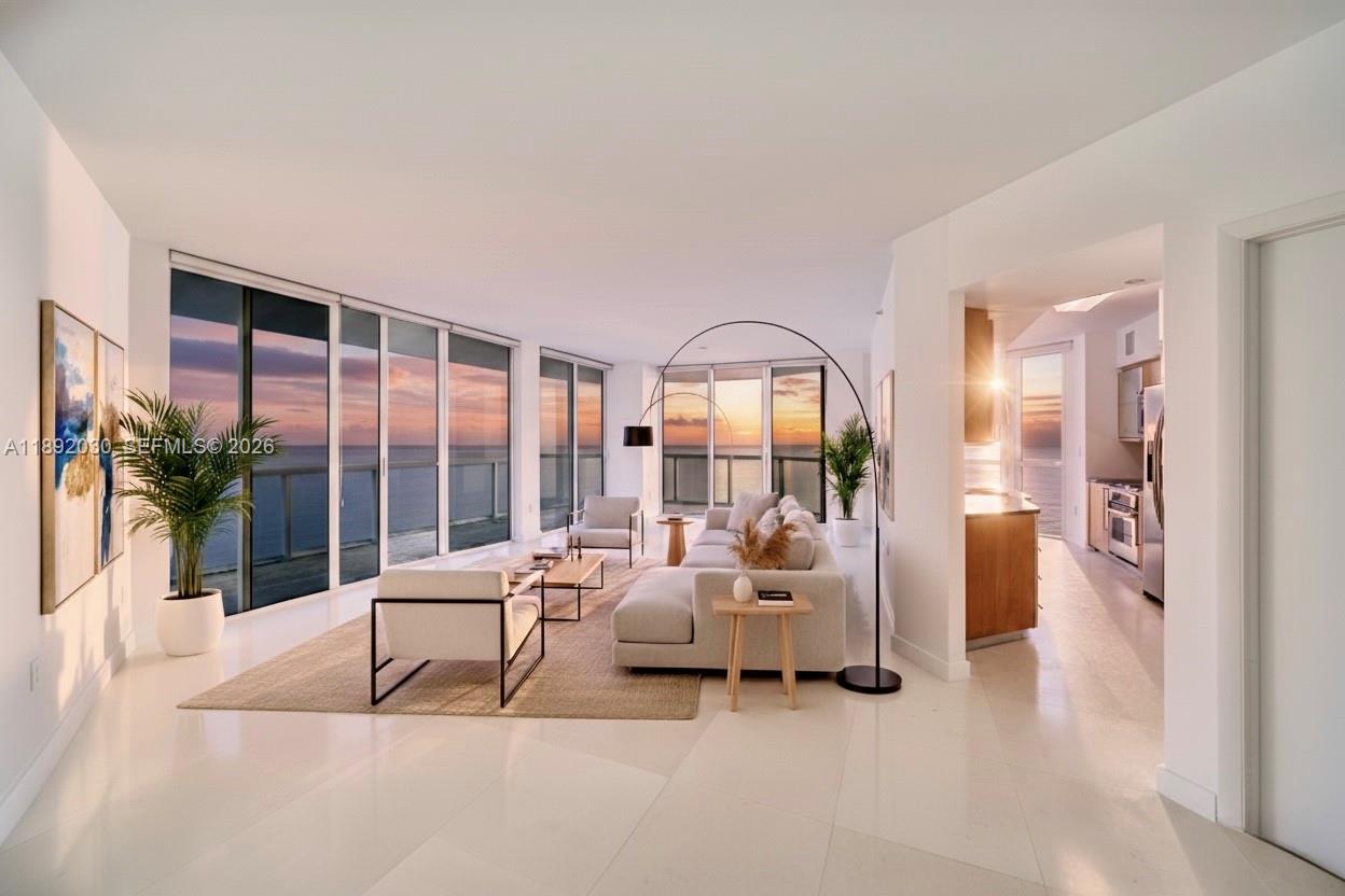 A modern living room features floor-to-ceiling windows with ocean views and light tile flooring — 6365 Collins Ave # 2901, Miami Beach FL 33141, MIAMI BEACH, FL