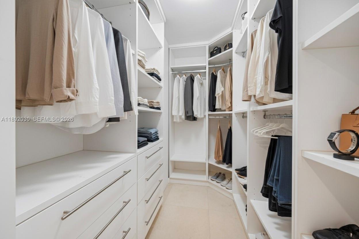 A walk-in closet features white shelving, hanging rods, and drawers with modern metal hardware — 6365 Collins Ave # 2901, Miami Beach FL 33141, MIAMI BEACH, FL