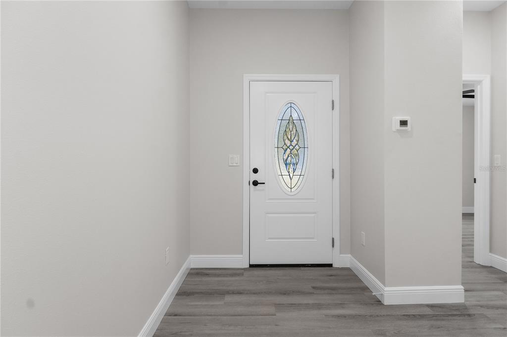 An entryway features a white front door with a decorative oval glass insert and flooring — 1768 E BISMARK ST, HERNANDO, FL