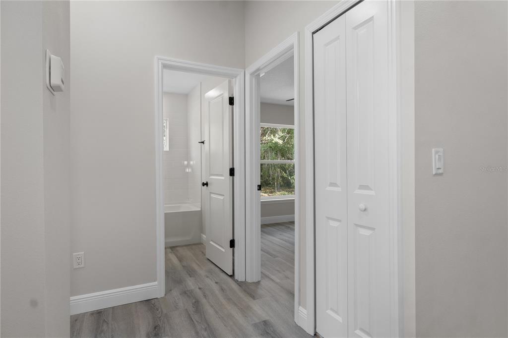 A hallway features light gray wood-look flooring, white walls, two doorways, and a bifold closet — 1768 E BISMARK ST, HERNANDO, FL