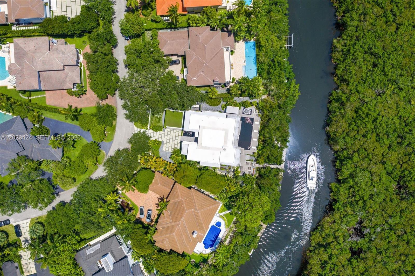 An aerial view shows several waterfront homes with swimming pools along a narrow canal — 132 Paloma Dr, Coral Gables FL 33143, CORAL GABLES, FL