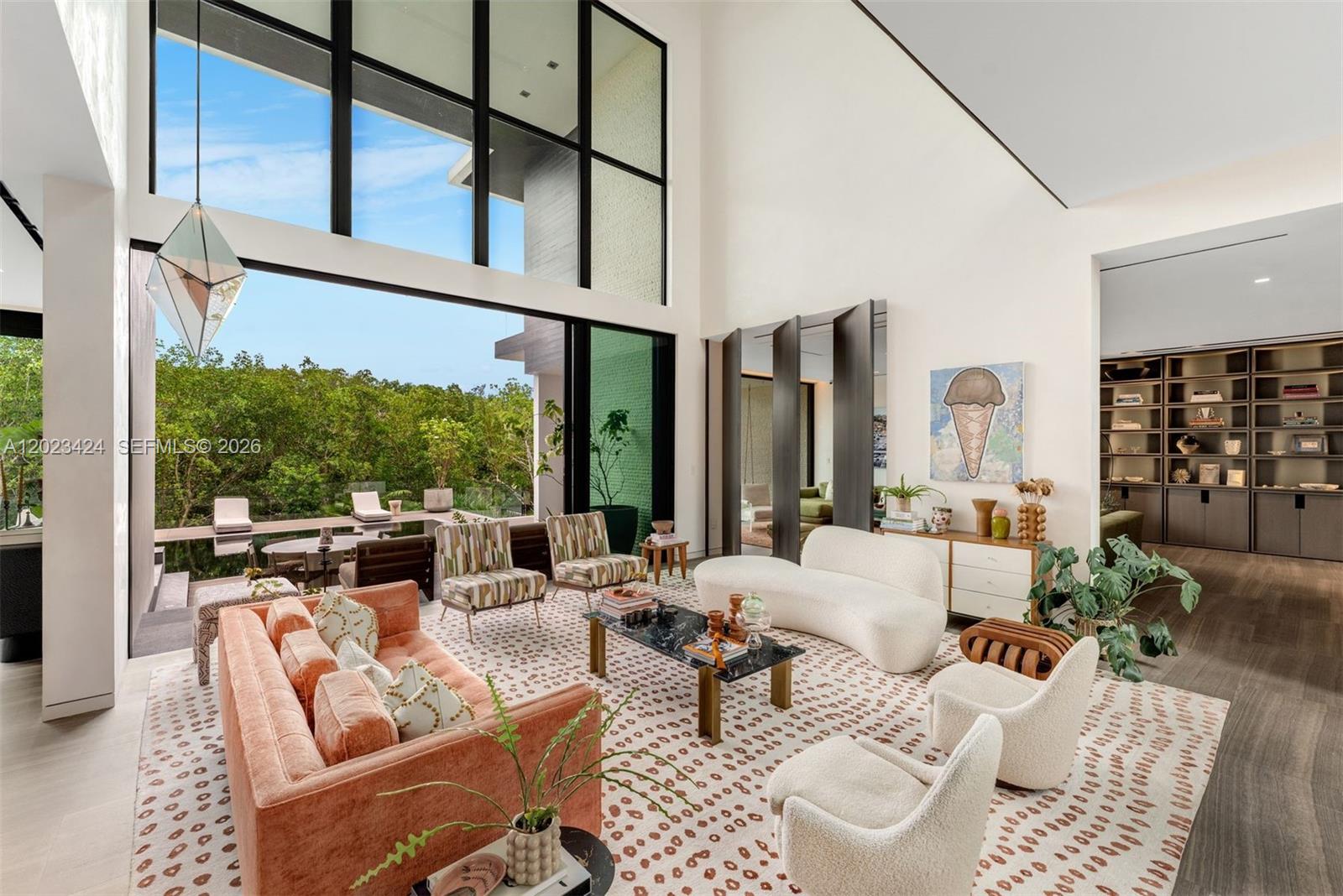 A modern living room features floor-to-ceiling windows, a patterned rug, and views of a pool — 132 Paloma Dr, Coral Gables FL 33143, CORAL GABLES, FL