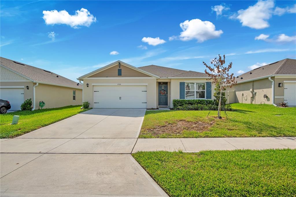 A single-story suburban house with a two-car garage, tan siding, and a front lawn — 3768 BOTANICAL WAY, SANFORD, FL