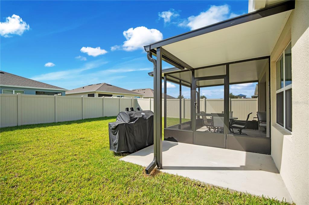 A backyard features a concrete patio with a screened-in enclosure and a covered roof — 3768 BOTANICAL WAY, SANFORD, FL