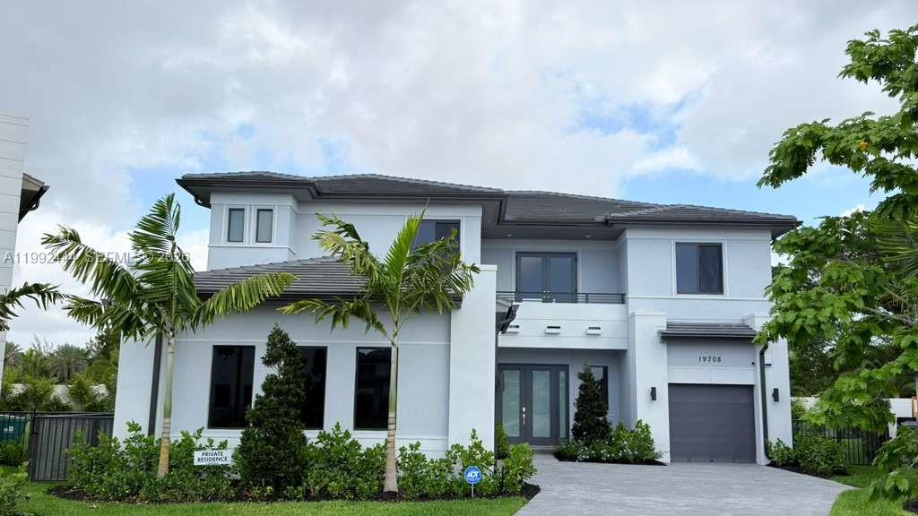 A two-story, light-gray modern house with a garage, palm trees, and a paved driveway — 19708 NE 14th Ave, Miami FL 33179, MIAMI, FL