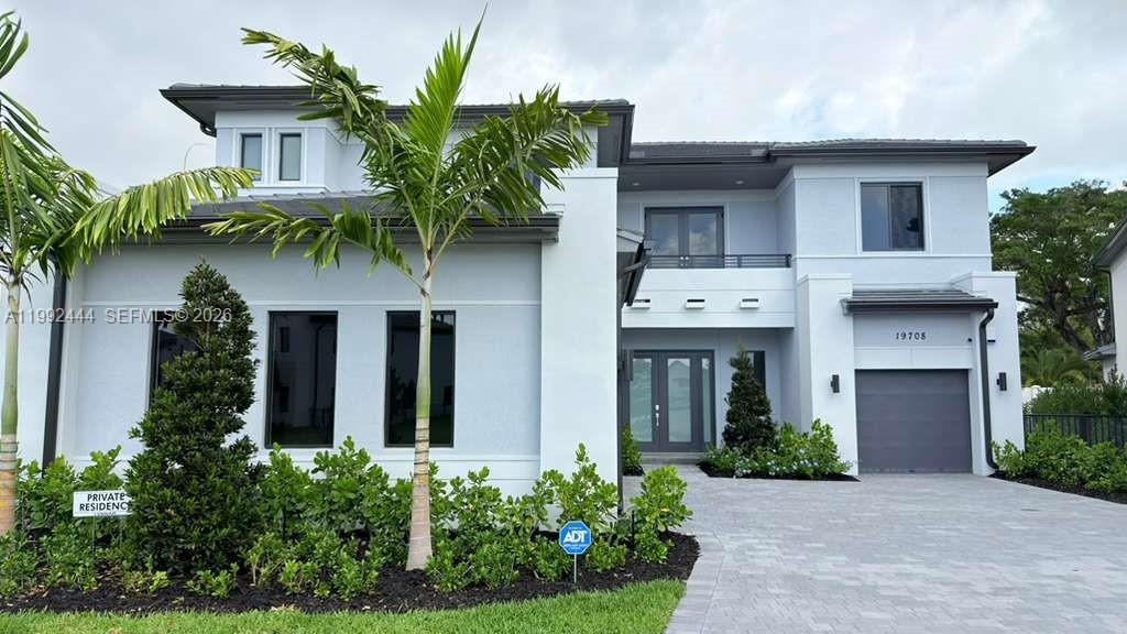 A two-story modern house features a gray exterior, a paved driveway, and a palm tree — 19708 NE 14th Ave, Miami FL 33179, MIAMI, FL