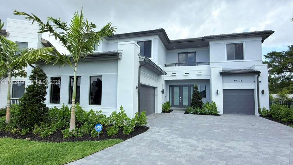 A two-story light gray house with a paved driveway, palm trees, and two garage doors — 19708 NE 14th Ave, Miami FL 33179, MIAMI, FL