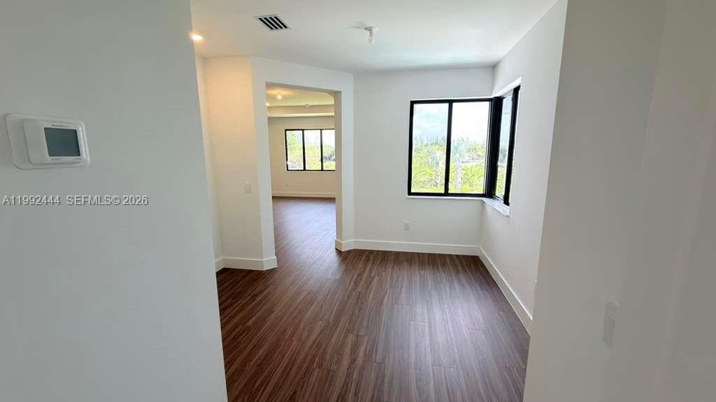 A room with wood-look flooring and a large window looking out onto greenery — 19708 NE 14th Ave, Miami FL 33179, MIAMI, FL