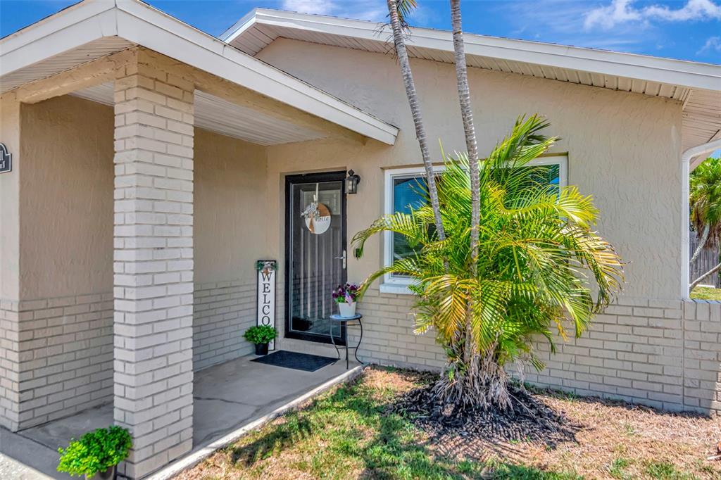 The exterior of a house features a brick-accented porch, a front door, and a palm tree — 7001 70TH AVENUE N, PINELLAS PARK, FL