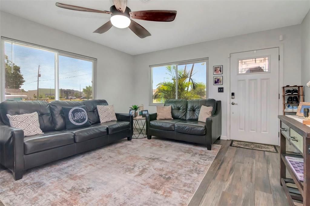 A living room features a dark leather sofa and loveseat on a patterned area rug — 7001 70TH AVENUE N, PINELLAS PARK, FL