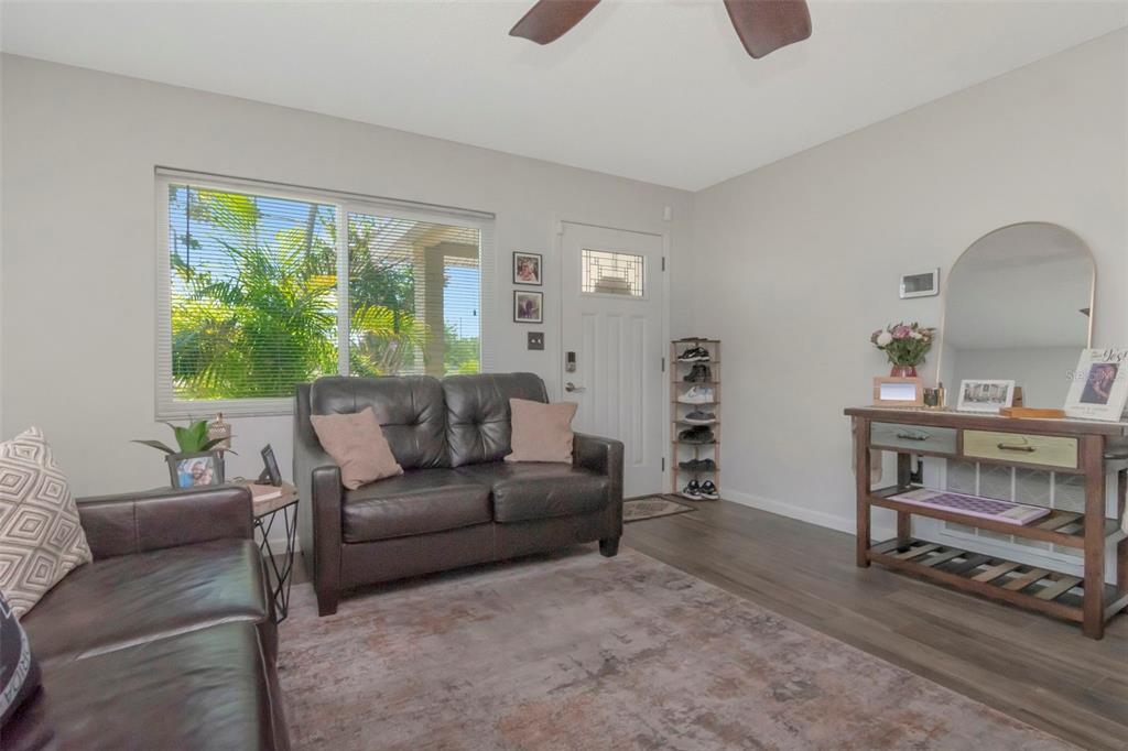 A living room features a dark leather sofa, a console table, and a front door — 7001 70TH AVENUE N, PINELLAS PARK, FL