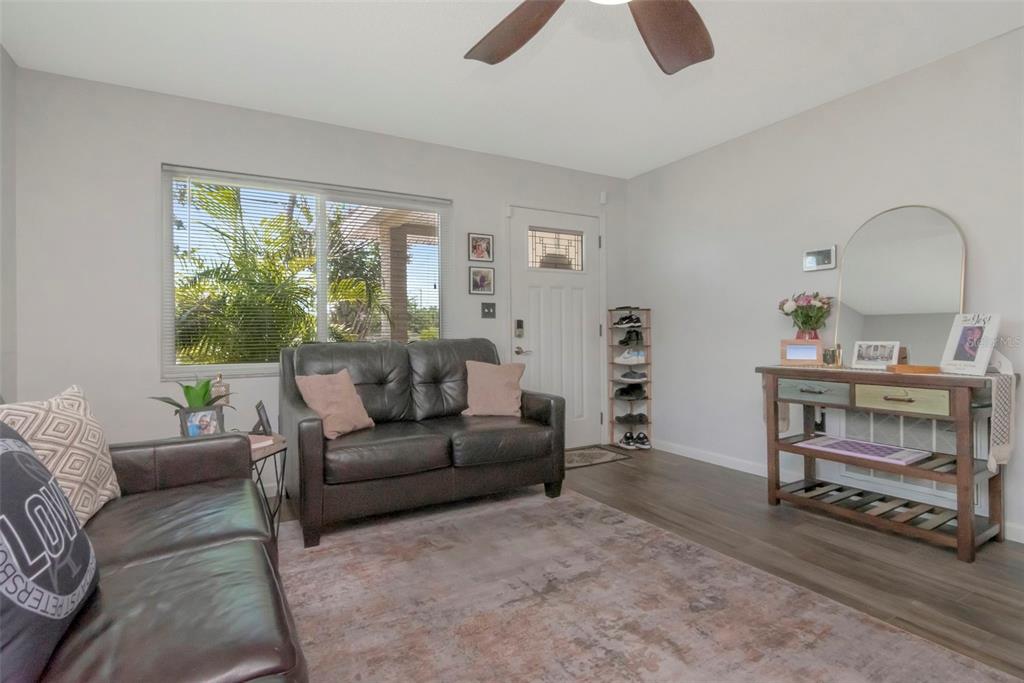 A living room features dark leather sofas, a wooden console table, and a window — 7001 70TH AVENUE N, PINELLAS PARK, FL