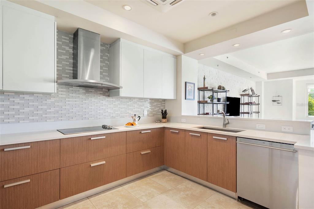 A modern kitchen features white upper cabinets, wood-toned lower cabinets, and a tiled backsplash — 500 PLANTATION DRIVE UNIT 3206, DORADO, PR