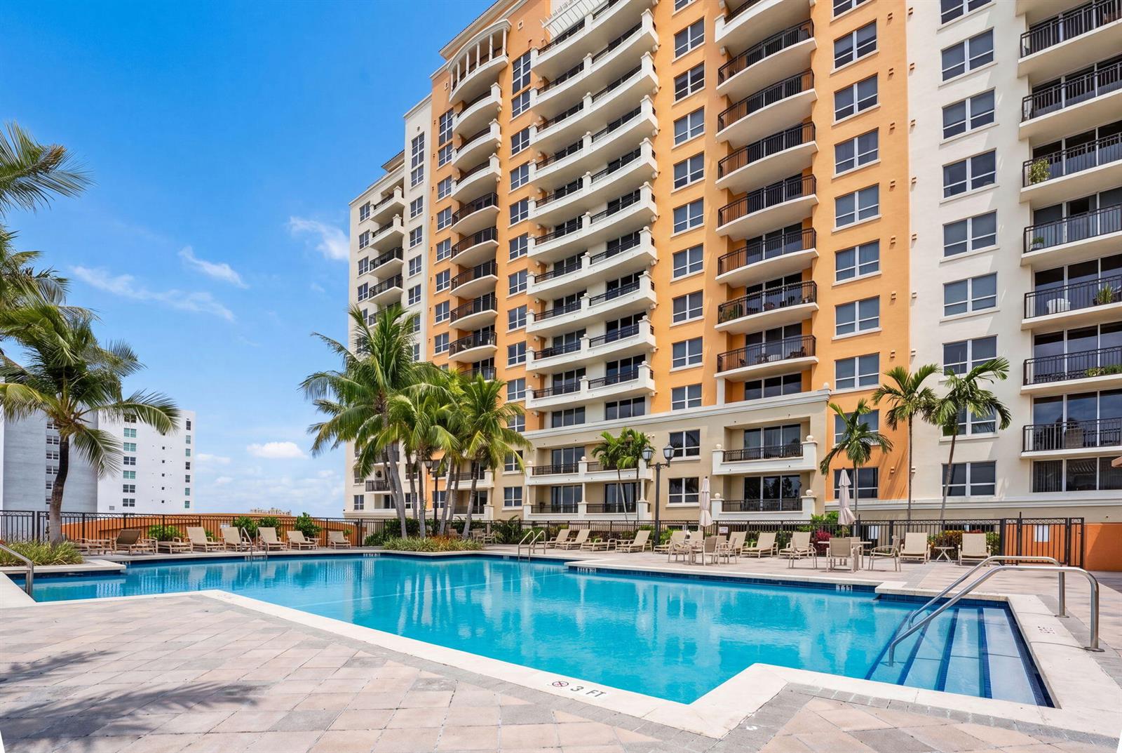 A large multi-story apartment building overlooks a swimming pool with lounge chairs and palm trees — 3232 Coral Way # 1601, Miami FL 33145, MIAMI, FL