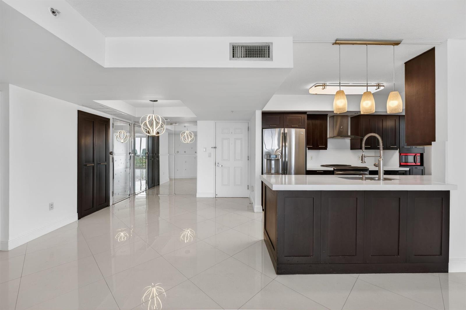 A modern kitchen with dark wood cabinets, white countertops, and tile flooring in an open-concept space — 3232 Coral Way # 1601, Miami FL 33145, MIAMI, FL