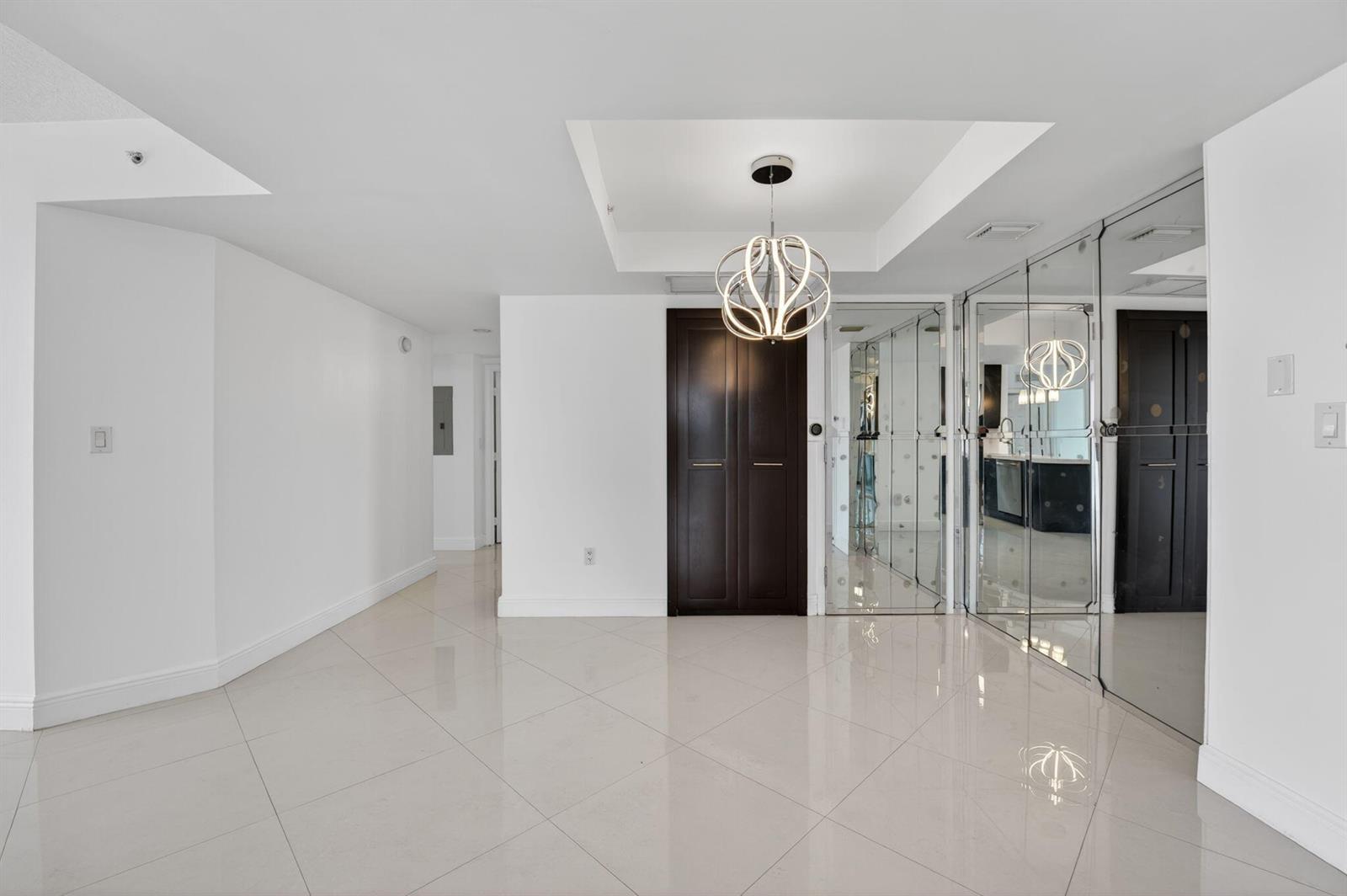 A bright entryway features white tile floors, a modern pendant light, and mirrored closet doors — 3232 Coral Way # 1601, Miami FL 33145, MIAMI, FL