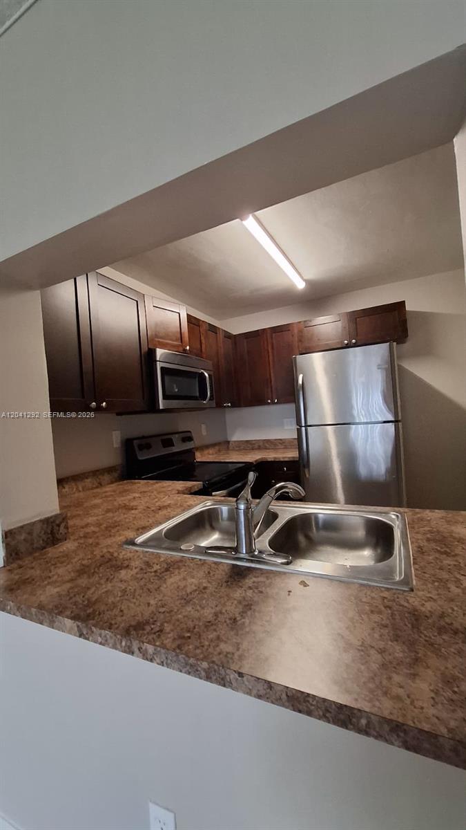 A kitchen features dark wood cabinets, stainless steel appliances, and a double-basin sink — 496 NW 165th St Rd # 612, Miami FL 33169, MIAMI, FL