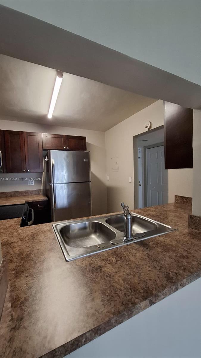 A kitchen features dark wood cabinets, stainless steel appliances, and a double-basin sink — 496 NW 165th St Rd # 612, Miami FL 33169, MIAMI, FL