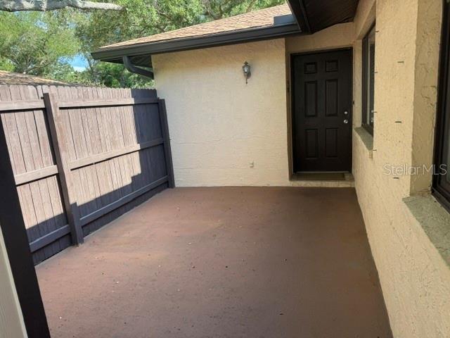 A small, paved outdoor patio area features a dark wooden fence and a dark entry door — 8472 60TH STREET N, PINELLAS PARK, FL