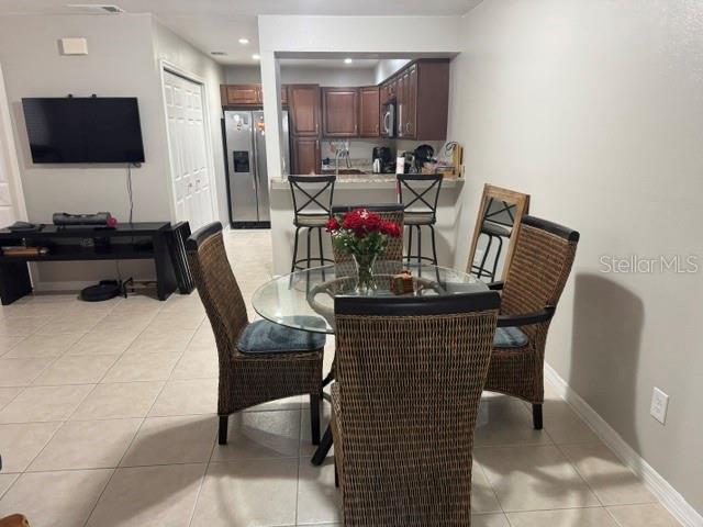A dining area with a glass table and wicker chairs sits before an open kitchen — 8472 60TH STREET N, PINELLAS PARK, FL