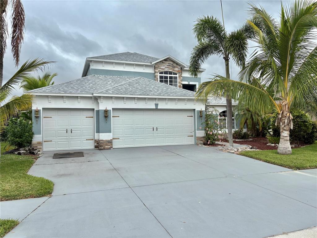 A two-story house with a three-car garage, stone accents, and palm trees in the yard — 6346 BOBBY JONES COURT, PALMETTO, FL
