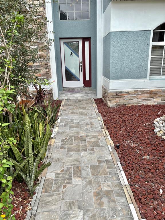 A tiled walkway leads to the front entrance of a house with stone accents — 6346 BOBBY JONES COURT, PALMETTO, FL