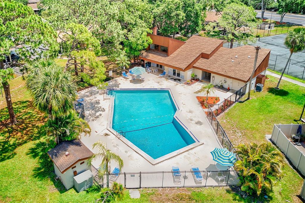 An aerial view of a swimming pool area with a clubhouse, tennis court, and landscaping — 2064 SUNSET POINT ROAD UNIT 73, CLEARWATER, FL