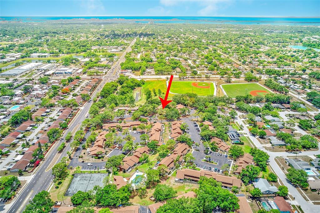 Aerial view of a residential apartment complex with a red arrow pointing to a building — 2064 SUNSET POINT ROAD UNIT 73, CLEARWATER, FL