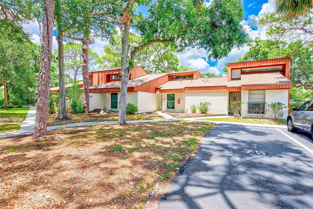 A single-story residential building with wood siding and a parking space in the foreground — 2064 SUNSET POINT ROAD UNIT 73, CLEARWATER, FL