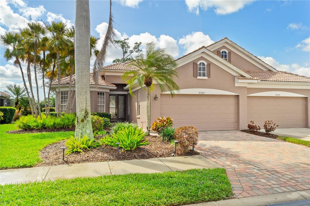 A single-story house with a tan stucco exterior, a tile roof, and a paved driveway — 5359 WHITE IBIS DRIVE, NORTH PORT, FL
