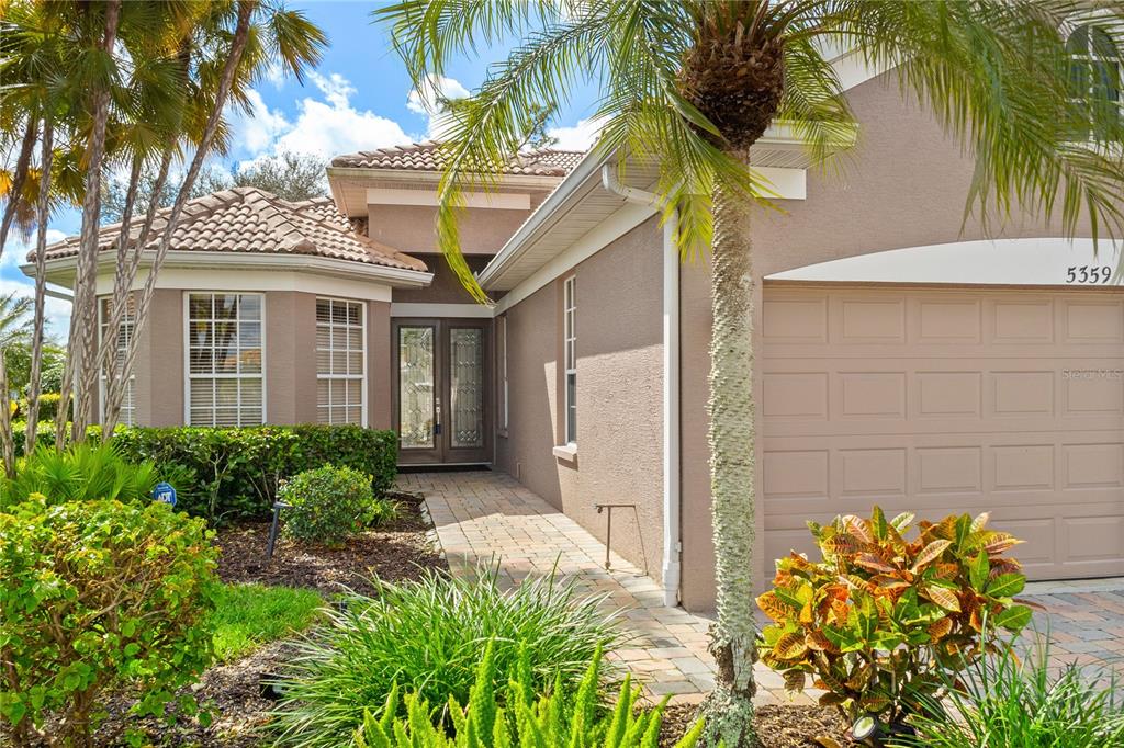 A single-story house with a tan stucco exterior, a tiled roof, and a paved walkway — 5359 WHITE IBIS DRIVE, NORTH PORT, FL