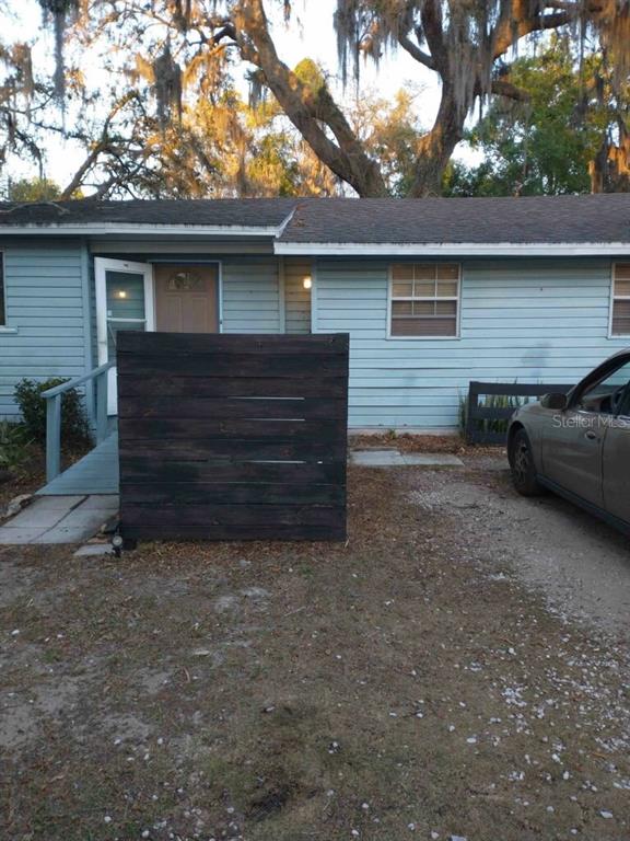 A light blue house exterior features a dark wooden privacy screen and a wheelchair ramp — 1611 INDIAN TRAIL, LEESBURG, FL