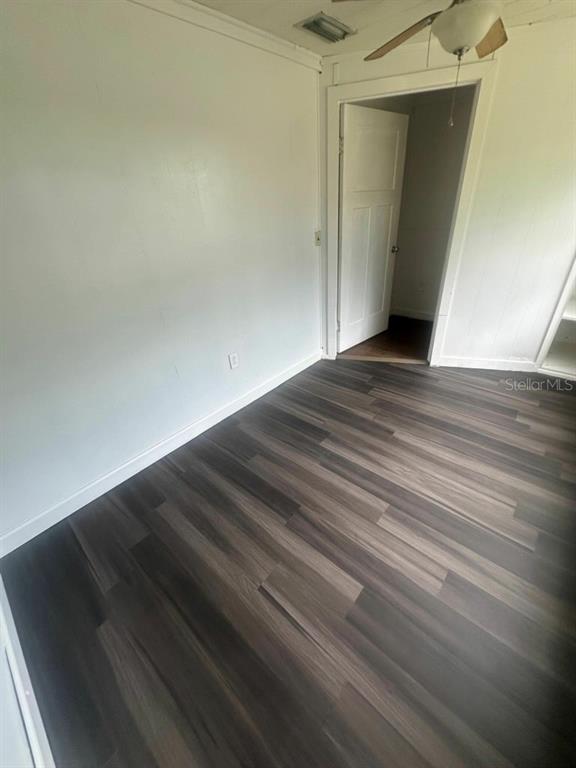 An empty room features wood-look laminate flooring, white walls, and an open doorway — 1611 INDIAN TRAIL, LEESBURG, FL