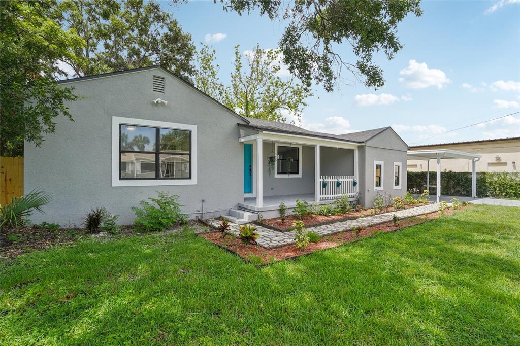 A gray stucco house with a covered front porch, blue door, and stone walkway — 3710 W GRIFLOW STREET, TAMPA, FL