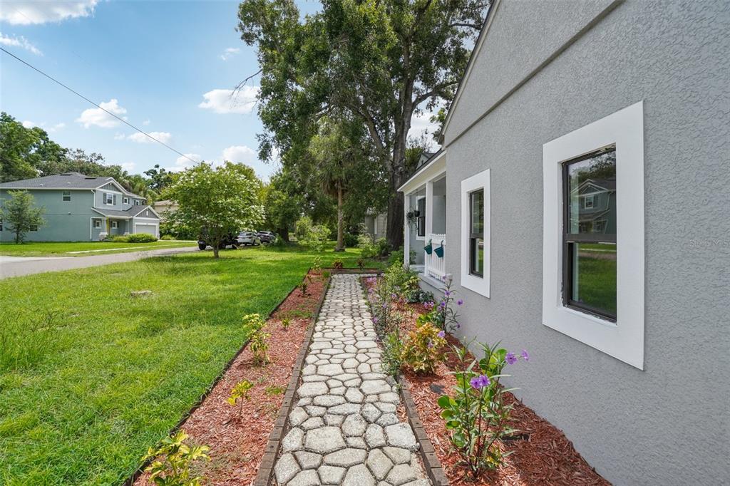 A stone walkway leads along the side of a gray house with a small porch — 3710 W GRIFLOW STREET, TAMPA, FL