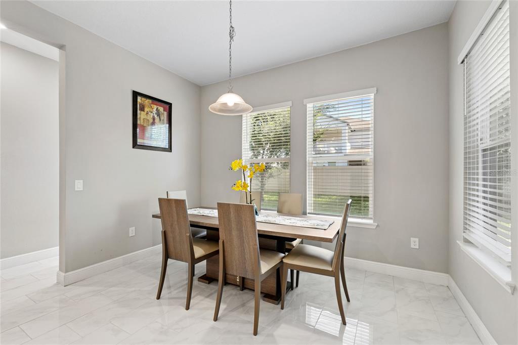 A dining room features a wooden table, four chairs, a pendant light, and tiled floors — 15031 GUAVA BAY DRIVE, WINTER GARDEN, FL