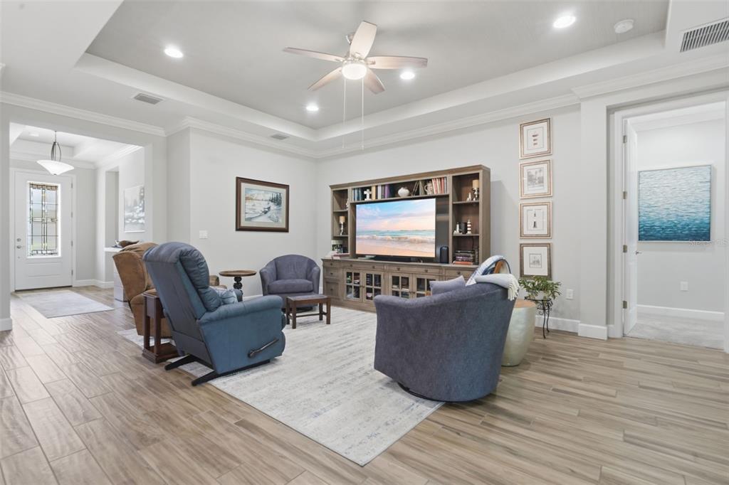 A living room features a tray ceiling, wood-look tile floors, and a large media console — 103 OLD MOSS CIRCLE, DELAND, FL