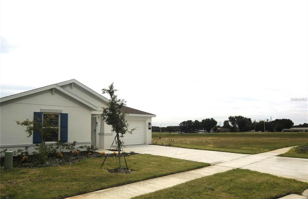 A single-story house with a white exterior, blue shutters, and a concrete driveway — 172 INMAN BOULEVARD, WINTER HAVEN, FL