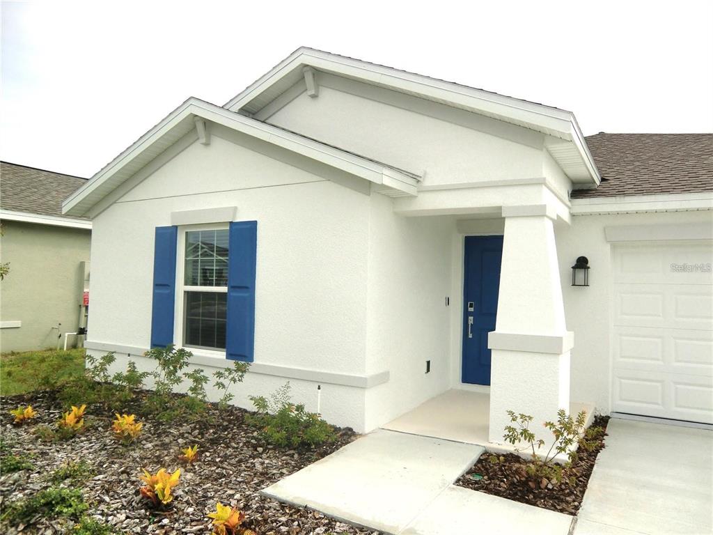 A single-story house with white stucco walls, blue shutters, a blue front door, and landscaping — 172 INMAN BOULEVARD, WINTER HAVEN, FL