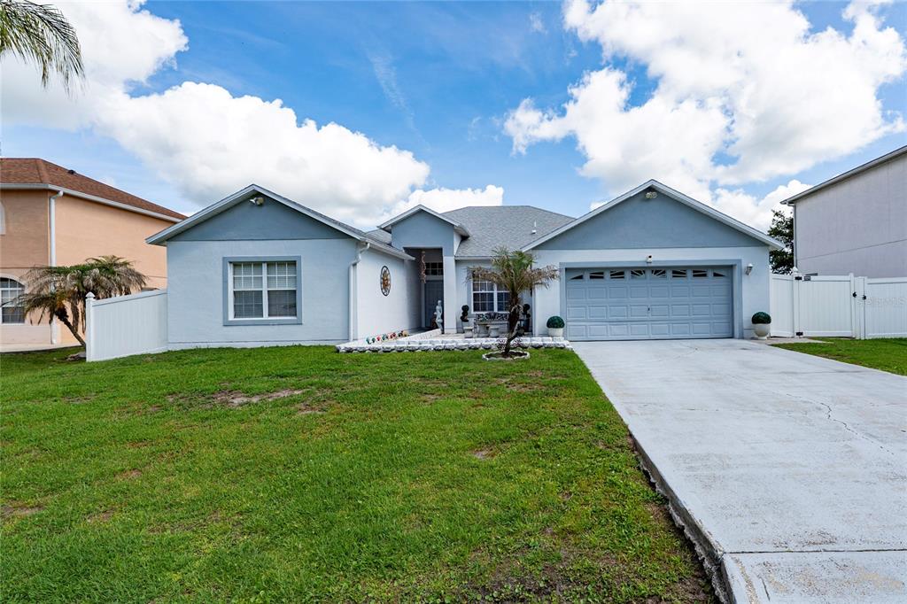 A single-story house with a light blue exterior, a two-car garage, and a front lawn — 661 ELBRIDGE DRIVE, KISSIMMEE, FL