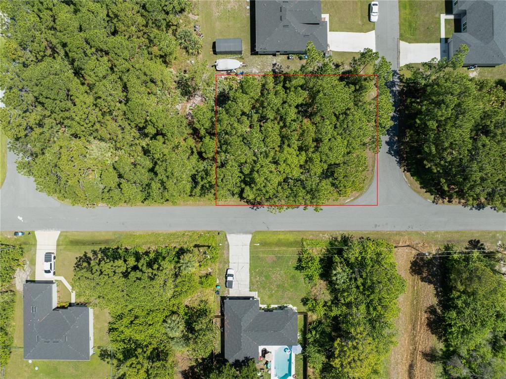 An aerial view shows a vacant, wooded residential lot outlined in red along a street — GABBOYS AVENUE SE, PALM BAY, FL