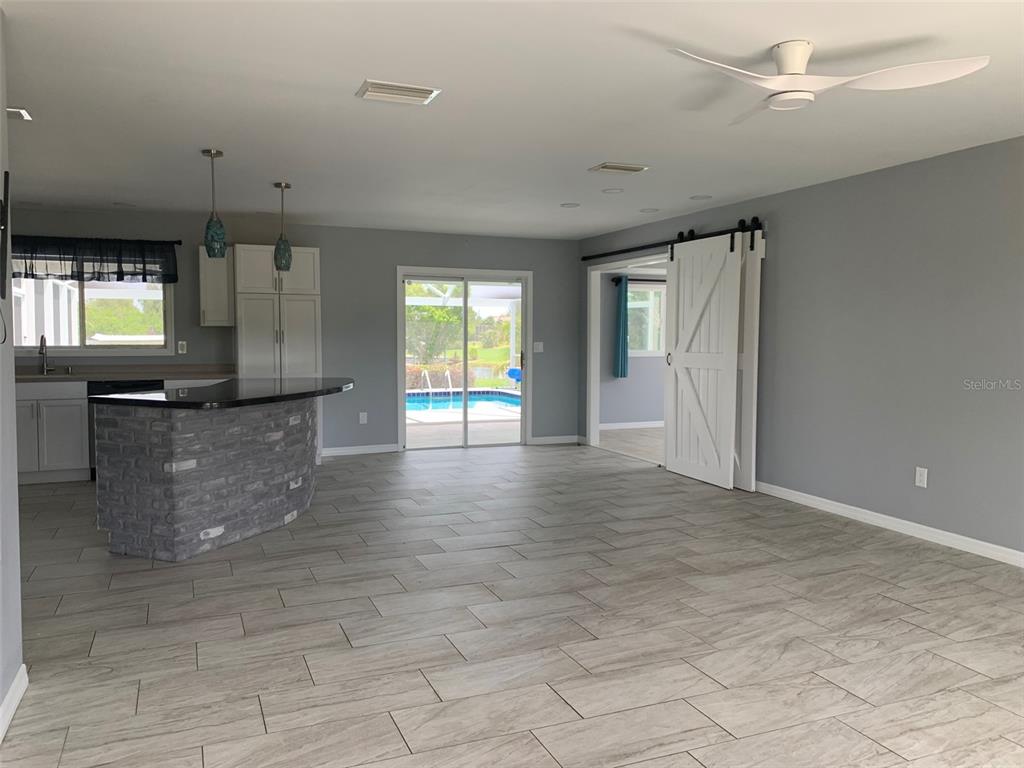 A kitchen with a stone-faced island opens to a living area with sliding glass doors — 9500 ATTICA CIRCLE, PORT CHARLOTTE, FL