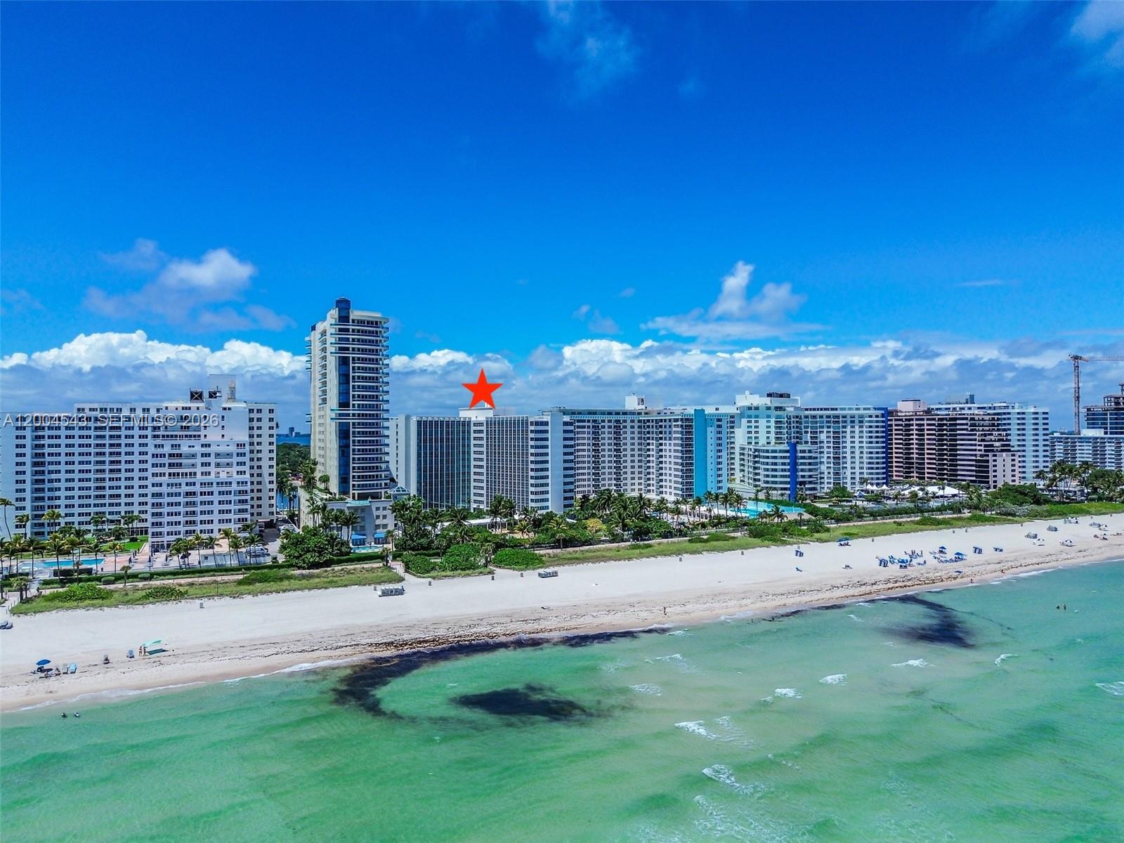 An aerial view of a beach with high-rise apartment buildings along the coastline — 5055 Collins Ave # 3K, Miami Beach FL 33140, MIAMI BEACH, FL