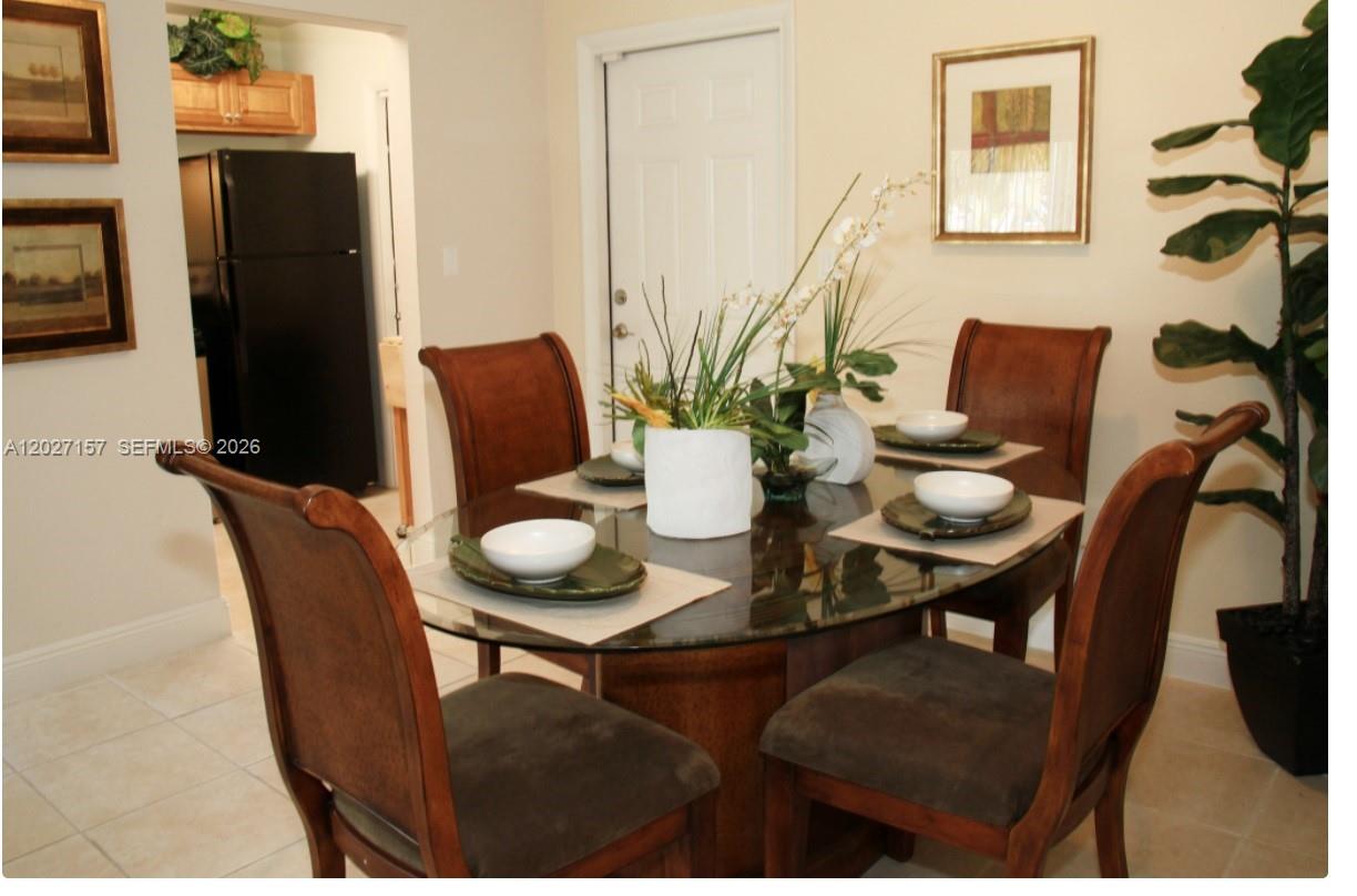 A dining room features a glass-topped table with four chairs and a nearby kitchen entrance — 4271 NW 5th St # 117, Plantation FL 33317, PLANTATION, FL