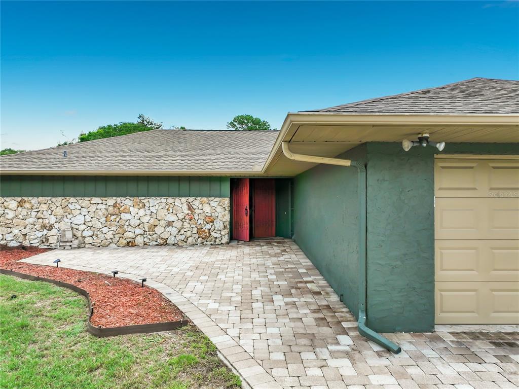 A paved patio features a dining set and a grill next to a fenced backyard — 6193 VALERIAN BOULEVARD, ORLANDO, FL