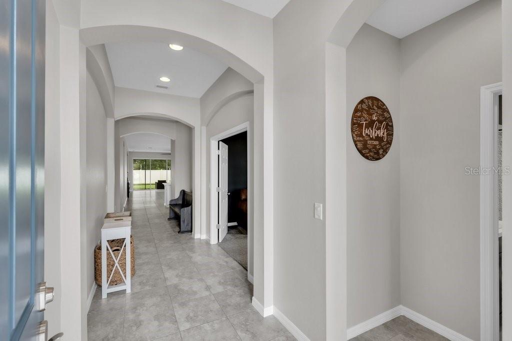 A bright entryway with tile flooring leads into a hallway with arched architectural details — 17651 BRIGHT WHEAT DRIVE, LITHIA, FL