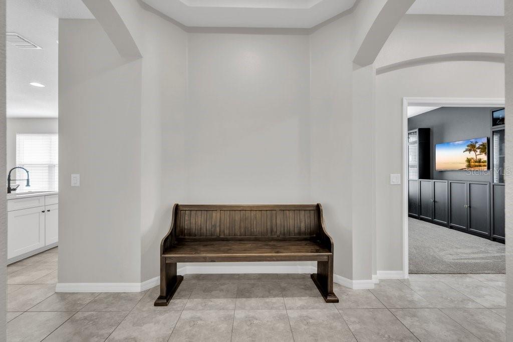 A wooden bench sits in a tiled entryway between a white kitchen and a room — 17651 BRIGHT WHEAT DRIVE, LITHIA, FL